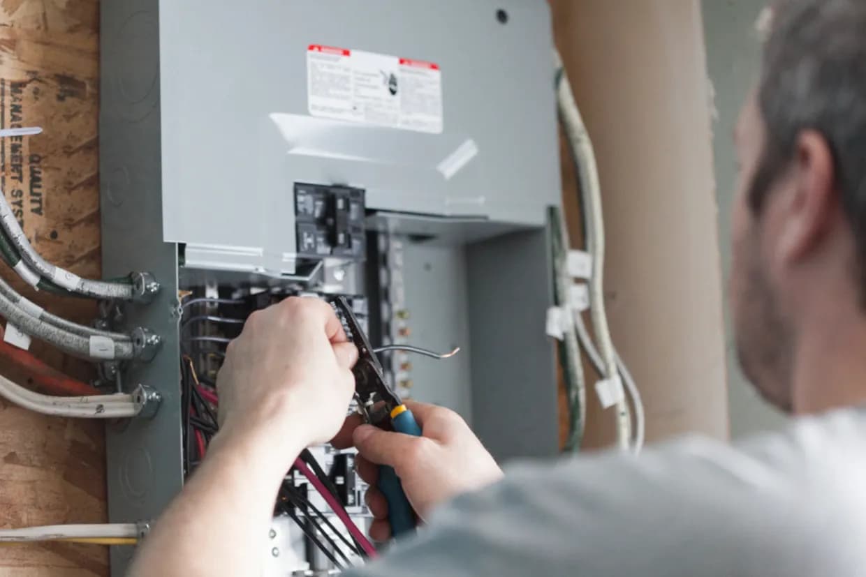 Electrician carefully working on wiring inside a breaker panel